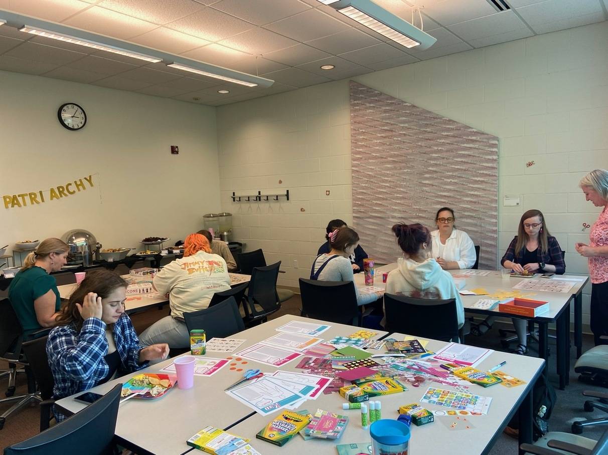 a photo of a decorated meeting room with crafting supplies and attendees creating their own Barbie characters